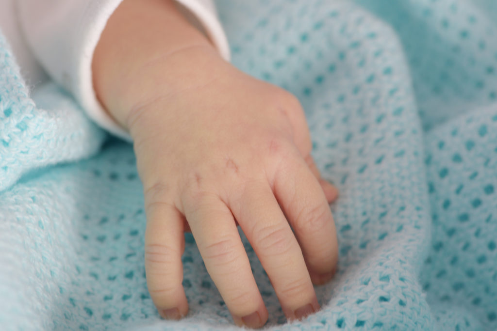 hand of the newborn baby on the blue blanket