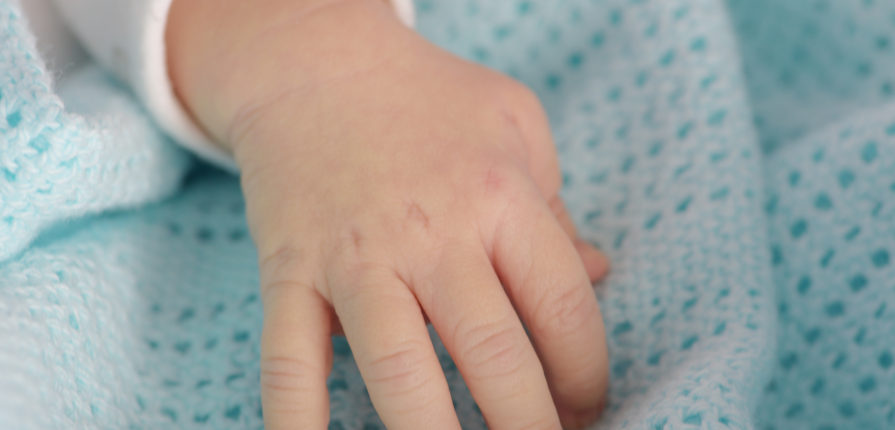 hand of the newborn baby on the blue blanket